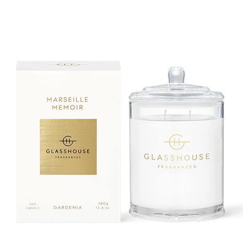 A product from Glasshouse Fragrances named ‘Marseille Memoir.’ The image shows a white-colored packaging box with gold lettering on the left and a candle in a glass container with a lid on the right. The box indicates that it is a soy candle , weighing 380g or 13.4 oz.