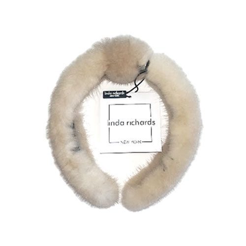 A ivory mink fur headband with a knot in the middle. The label has black text that reads “linda richards NEW YORK.”