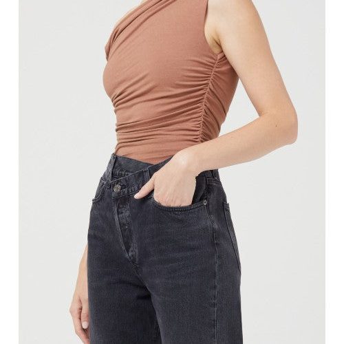 Model wearing skintone one-shoulder bodysuit with black denim jeans.